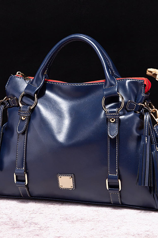 Blue leather handbag with gold accents on a dark background