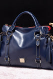 Blue leather handbag with gold accents on a dark background