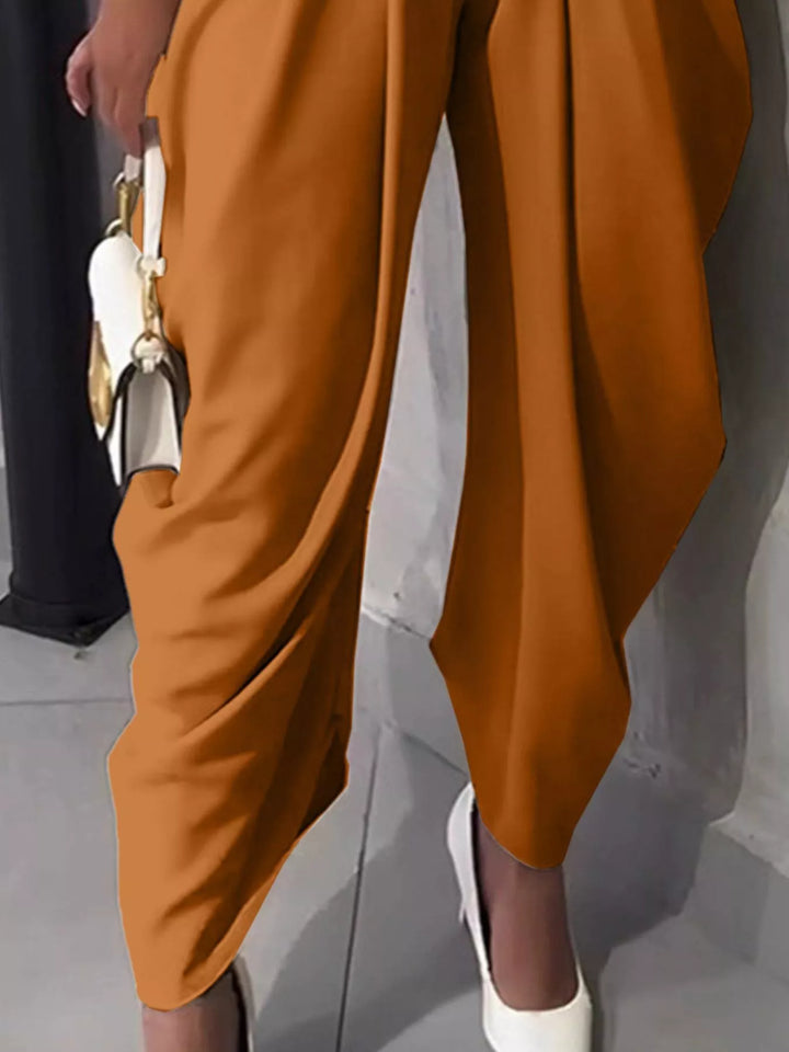 Brown pants being worn with a white shoe on a neutral background