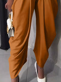 Brown pants being worn with a white shoe on a neutral background