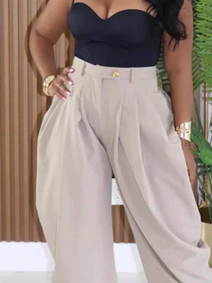 Person wearing a black strapless top and beige high-waisted pants with a blurred background