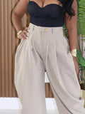 Person wearing a black strapless top and beige high-waisted pants with a blurred background