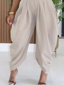Brown pants being worn with a white shoe on a neutral background