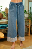 Blue denim pants with lace trim worn by a person indoors.