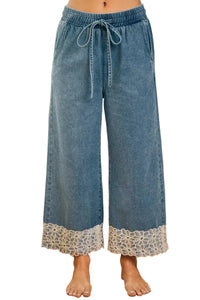Blue denim pants with lace trim worn by a person indoors.