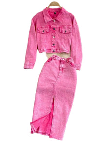 Pink denim jacket and pants set on a gray surface with decorative flowers in the background