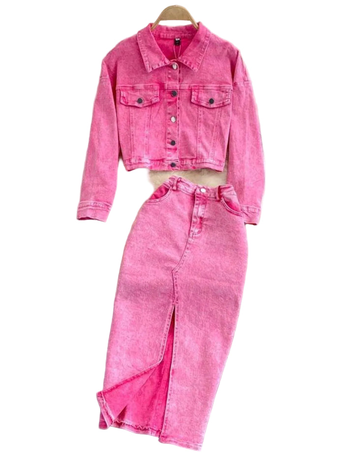 Pink denim jacket and pants set on a gray surface with decorative flowers in the background