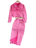 Pink denim jacket and pants set on a gray surface with decorative flowers in the background