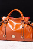 Brown leather handbag with gold accents on a black background