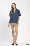 Woman wearing a blue denim shirt and beige shorts on a white background