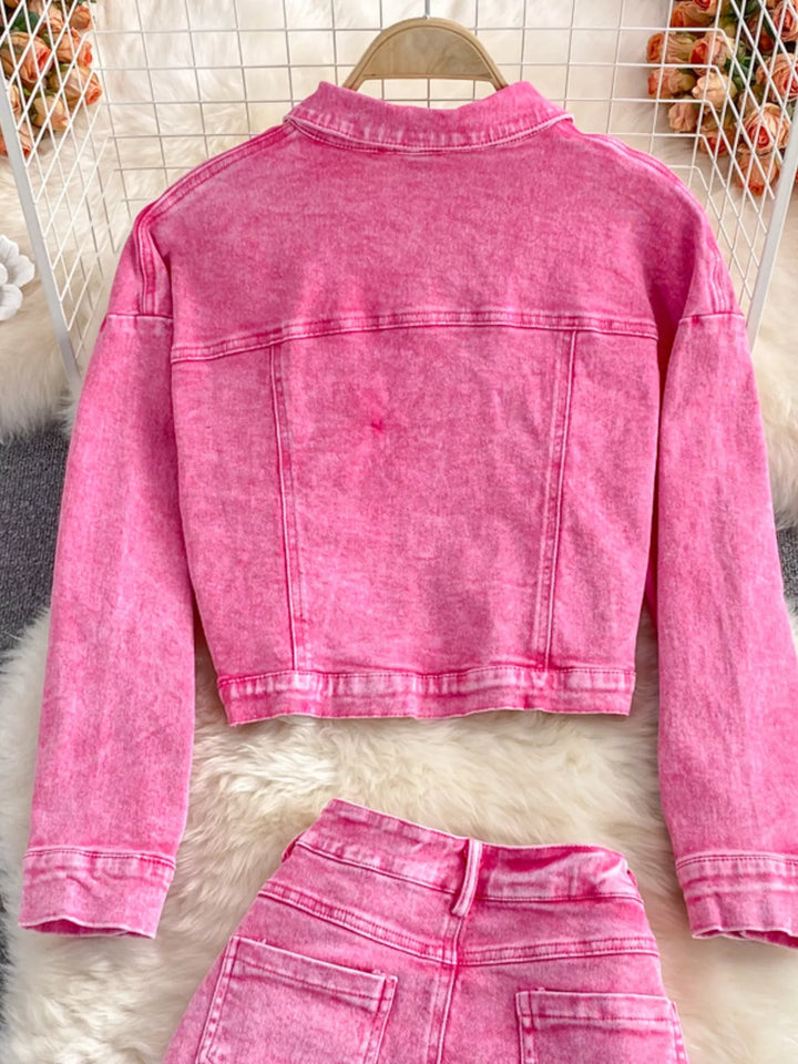Pink denim jacket and pants on a white fur surface with a blurred background