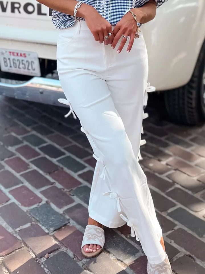Person wearing white jeans with lace details on a street.