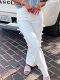 Person wearing white jeans with lace details on a street.