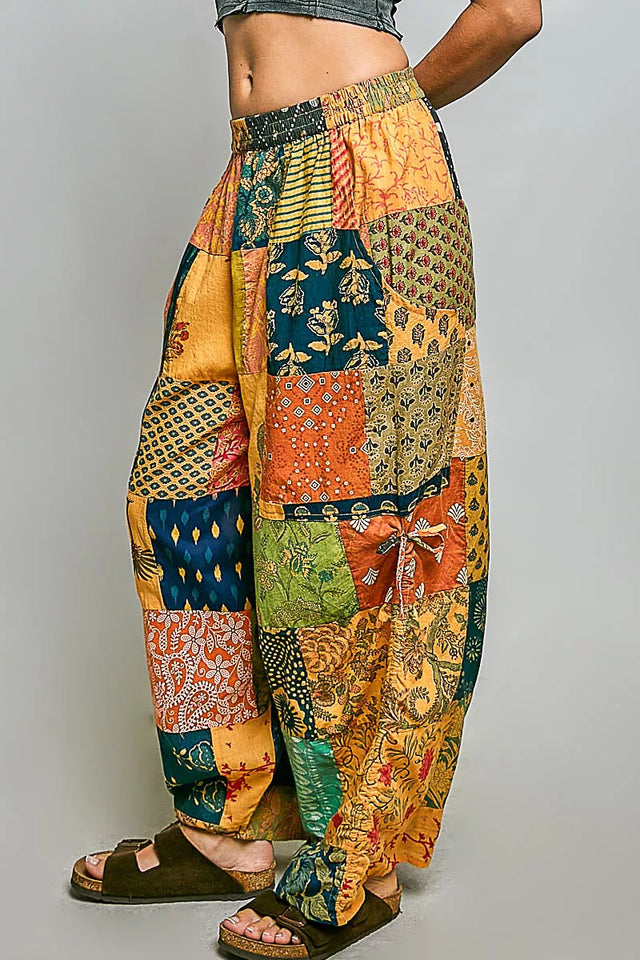 Colorful patchwork pants worn by a person on a gray background