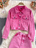 Pink denim jacket and pants set on a textured surface with decorative flowers in the background.