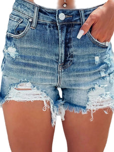 Close-up of a person wearing distressed denim shorts with a blurred background