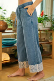 Person wearing blue jeans with lace cuffs in a home setting