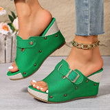 Green wedge sandals worn with denim jeans on a neutral background