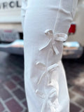 White long-sleeve top with bow details on a blurred background