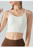 Woman wearing a white sports bra and brown leggings on a light gray background