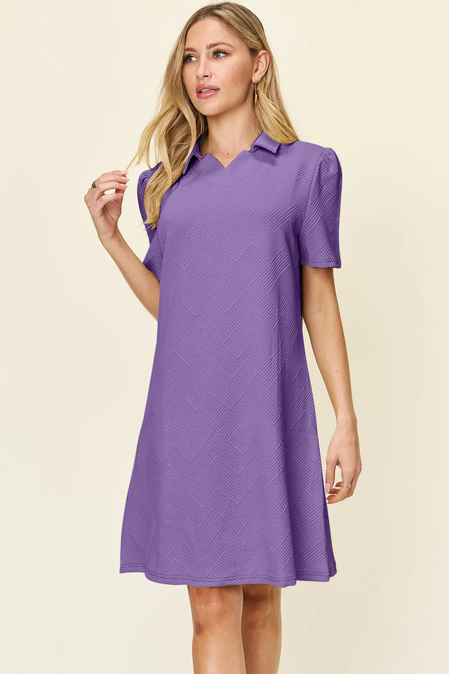 Woman wearing a purple dress with a collar on a beige background