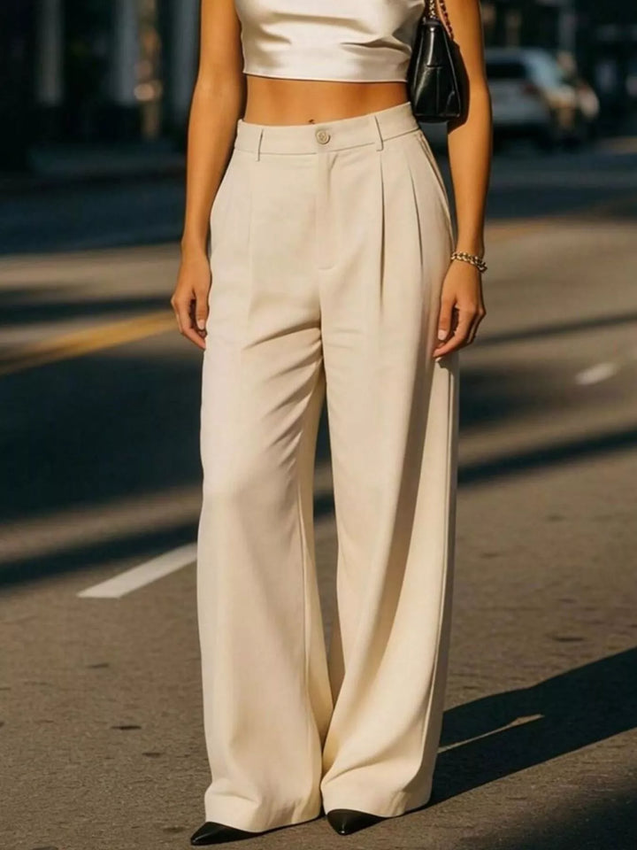 Person wearing a white top and beige wide-leg pants on a street.