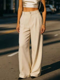 Person wearing a white top and beige wide-leg pants on a street.