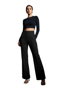Person wearing black high-waisted pants in a room with a white sofa and wooden floor.