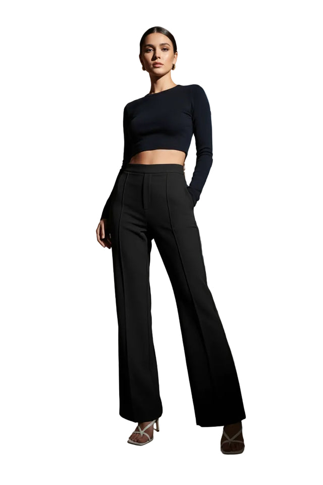 Person wearing black high-waisted pants in a room with a white sofa and wooden floor.