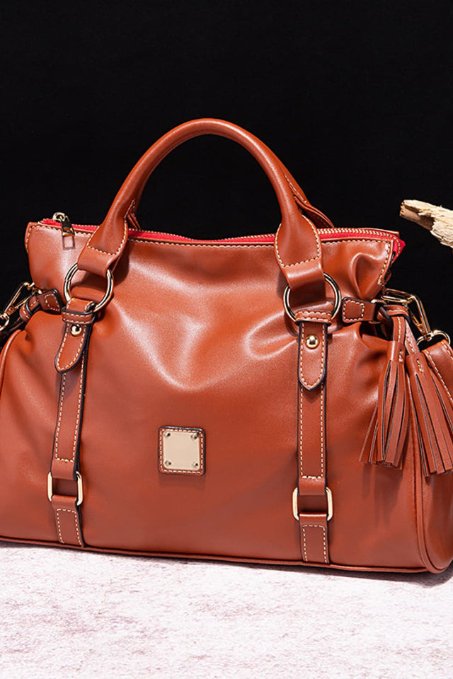 Brown leather handbag with gold accents on a black background