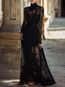 Black lace dress with long sleeves and sheer skirt against a blurred architectural background