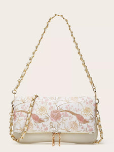 Floral patterned handbag with gold chain strap on a beige background
