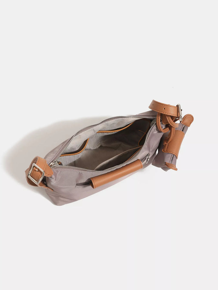 Gray crossbody bag with brown leather straps on a white background