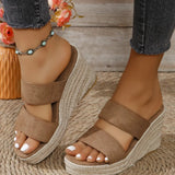 Brown wedge sandals worn with denim jeans on a wooden floor.