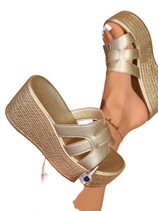 Gold platform sandals being worn with a neutral background