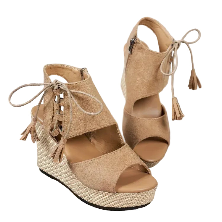Pair of tan wedge sandals with raffia sole on a wooden surface