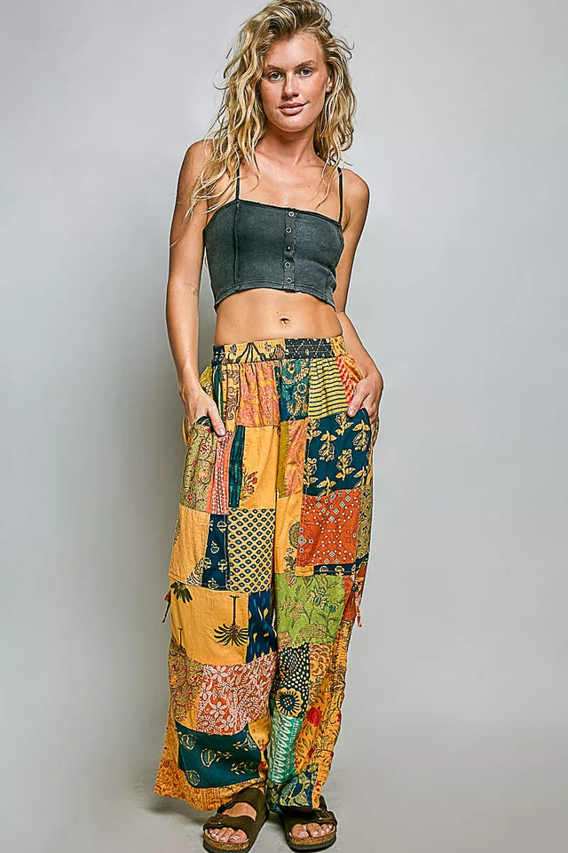 Woman wearing a colorful patchwork skirt and black top on a gray background