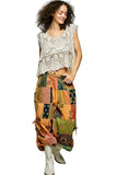 Woman wearing a patterned top and colorful patchwork skirt against a plain background