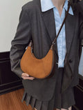Person wearing a dark suit with a light blue shirt and holding a brown leather bag.