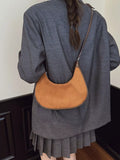 Person wearing a brown leather shoulder bag over their shoulder.