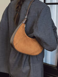 Person wearing a brown leather shoulder bag with a gray coat.