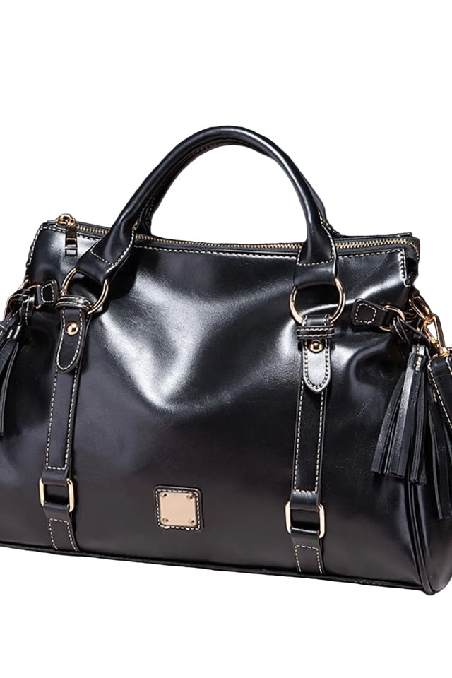 Black leather handbag with gold accents on a dark background