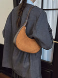 Person wearing a gray outfit with a brown leather bag over one shoulder.