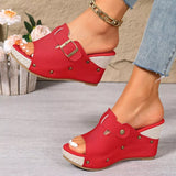 Red open-toe shoes with a buckle worn by a person on a neutral background