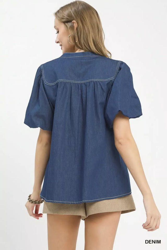 Woman wearing a blue denim shirt and beige shorts on a white background