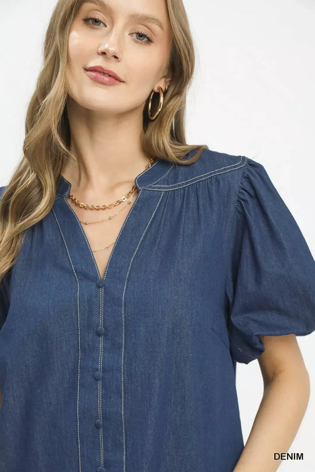 Woman wearing a blue denim dress with puff sleeves on a white background
