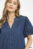 Woman wearing a blue denim dress with puff sleeves on a white background