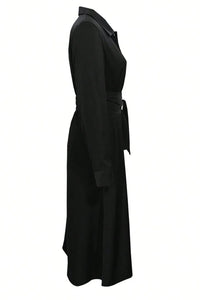 Black dress with a belt and a slit on a neutral background