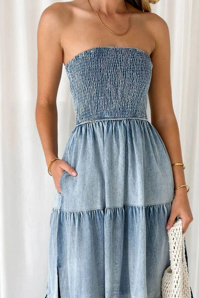 Woman wearing a strapless denim dress against a white background