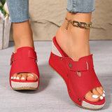 Red open-toe sandals with buckle details worn by a person on a neutral background